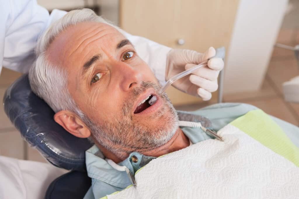 Dentist examining a patients teeth in the dentists chair